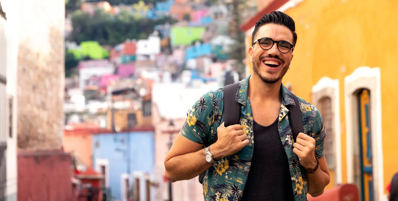 Emigrar a España siendo mexicano: joven feliz disfrutando de su nueva vida en España Emigrar a España siendo mexicano: hombre sonriente en las coloridas calles de España