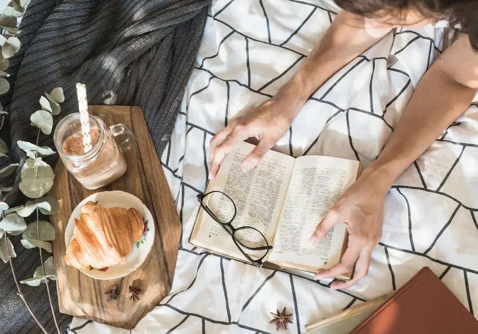 Mujer leyendo mientras desayuna tranquilamente, manera de slow livin.