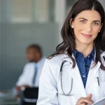 Homologación de títulos peruanos en España: médica con bata y estetoscopio en un hospital, revisando documentación en una tablet.