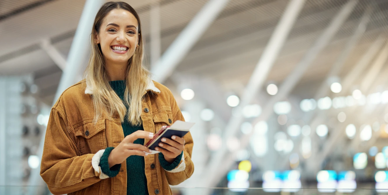 Mujer en un aeropuerto consultando su documentación de viaje para entender la diferencia entre visa y pasaporte antes de venir a España.