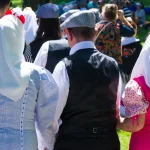 Personas con vestimenta tradicional participando en una celebración cultural representativa de tradiciones en España al aire libre.