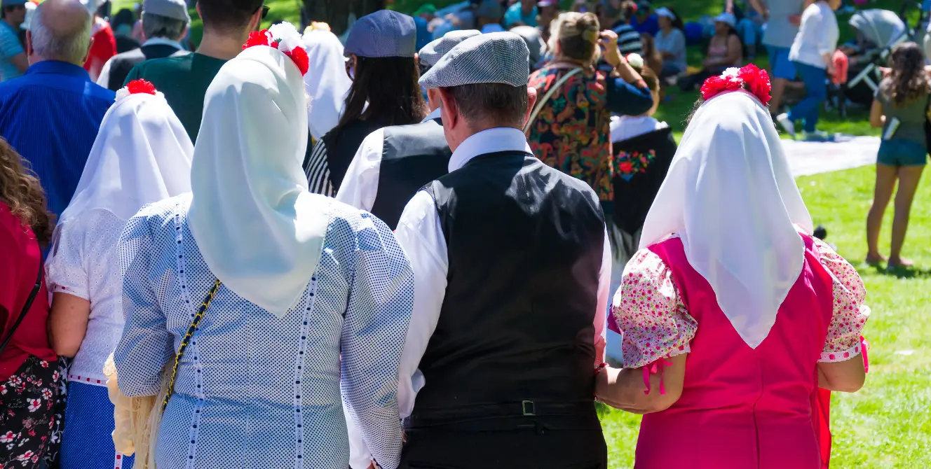 Personas con vestimenta tradicional participando en una celebración cultural representativa de tradiciones en España al aire libre.