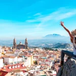 Vista panorámica de ciudad española con viajera disfrutando del paisaje tras cumplir los requisitos para viajar a España siendo mexicano.