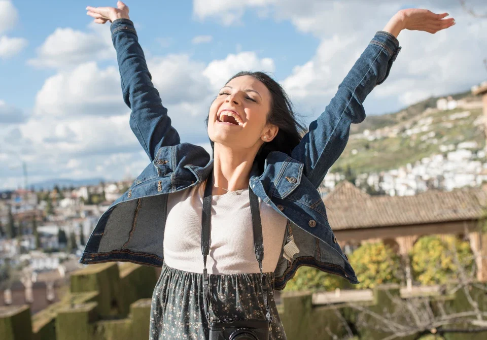 Mujer celebra con los brazos abiertos la calidad de vida en España en un mirador de Granada