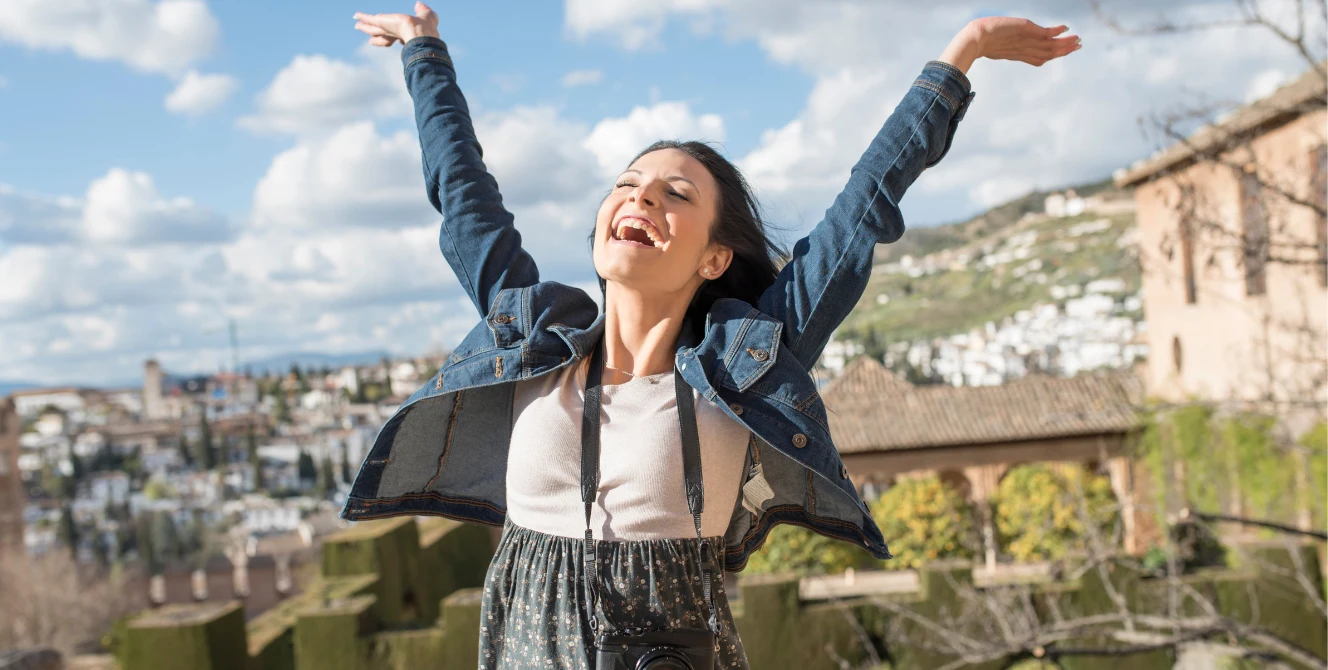 Mujer celebra con los brazos abiertos la calidad de vida en España en un mirador de Granada